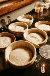Warm rustic kitchen scene with dough rising in woven baskets, ideal for artisanal and homemade baking theme.
